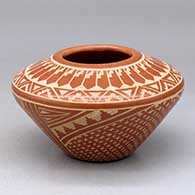 A red on buff jar decorated with a sgraffito snowflake, feather and geometric design
 by Wilma Baca Tosa of Jemez