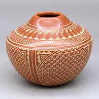 A red jar decorated with a four panel sgraffito spiral, snowflake, feather and geometric design
 by Wilma Baca Tosa of Jemez