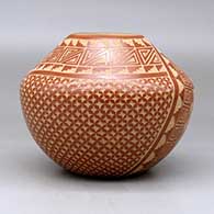 A red jar decorated with a two panel sgraffito spiral, snowflake and geometric design, click or tap to see a larger version