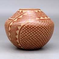 A red jar decorated with a two panel sgraffito spiral, snowflake and geometric design, click or tap to see a larger version