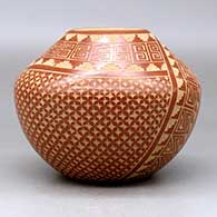 A red jar decorated with a two panel sgraffito spiral, snowflake and geometric design, click or tap to see a larger version