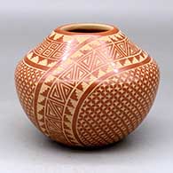 A red jar decorated with a two panel sgraffito spiral, snowflake and geometric design
 by Wilma Baca Tosa of Jemez