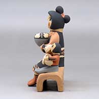 A Singing Mother figure sitting on an adobe wall with three children, a puppy and a pot, click or tap to see a larger version