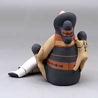 A sitting grandmother storyteller with five children, a folded manta and a welcome basket, click or tap to see a larger version