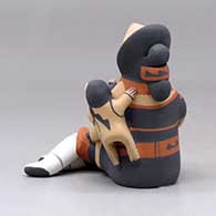 A sitting grandmother storyteller figure with three children, a football and a soccer ball, click or tap to see a larger version