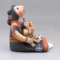 A sitting grandmother storyteller figure with three children, a football and a soccer ball, click or tap to see a larger version