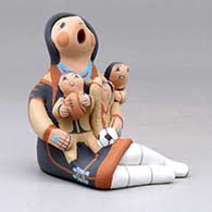 A sitting grandmother storyteller figure with three children, a football and a soccer ball, click or tap to see a larger version