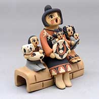 Click for a larger view A grandmother storyteller figure sitting on a stone wall with four children, a puppy and a welcome basket
 by Chrislyn Fragua of Jemez