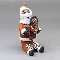 A sitting Santa Claus storyteller figure with two children and gifts
 by Felicia Fragua of Jemez