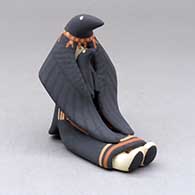 A sitting raven storyteller with one chick
 by Loren Wallowing Bull of Jemez