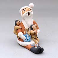 A sitting Santa Claus storyteller figure with two children, a puppy and gifts
 by Diane Lucero of Jemez