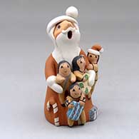 A standing Santa Claus storyteller figure with three children and gifts
 by Diane Lucero of Jemez