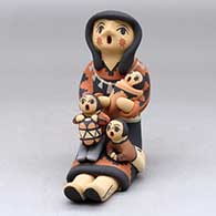A sitting grandmother storyteller figure holding three children and a drum
 by Chrislyn Fragua of Jemez
