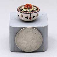 A miniature polychrome flat-topped jar decorated with a notched rim, cutouts and a flower and geometric design, click or tap to see a larger version