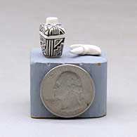 A miniature black on white lidded rectangular jar with a cutout in the lid and and decorated with a fineline and geometric design, click or tap to see a larger version