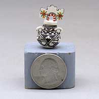 A miniature black on white jar with handles and a polychrome tablito lid and and decorated with a fineline, checkerboard and geometric design, click or tap to see a larger version