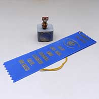A lidded, polychrome miniature Corn Maiden jar with a tablito on the lid and a geometric design, First Place ribbon from the Gallup InterTribal Ceremonial
 by Thomas Natseway of Laguna