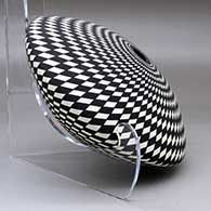 A black on white seed pot decorated with a spiraling checkerboard geometric design, click or tap to see a larger version