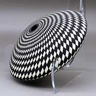 A black on white seed pot decorated with a spiraling checkerboard geometric design, click or tap to see a larger version