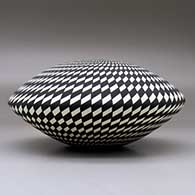 A black on white seed pot decorated with a spiraling checkerboard geometric design, click or tap to see a larger version