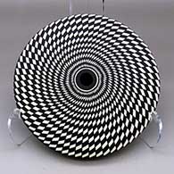 A black on white seed pot decorated with a spiraling checkerboard geometric design
 by Robert Kasero Sr of Laguna