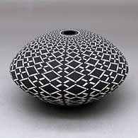 A black on white seed pot decorated with a spiral stylized checkerboard geometric design
 by Robert Kasero Sr of Laguna