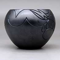 A micaceous black jar decorated with a lightly-carved avanyu, bear paw and geometric design, click or tap to see a larger version