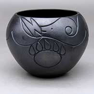 A micaceous black jar decorated with a lightly-carved avanyu, bear paw and geometric design
 by Robert Vigil of Nambe