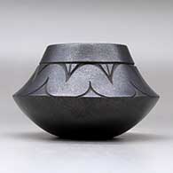 A micaceous black jar decorated with a lightly-carved avanyu and geometric design above the shoulder, click or tap to see a larger version