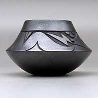 A micaceous black jar decorated with a lightly-carved avanyu and geometric design above the shoulder, click or tap to see a larger version