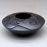 A low shouldered micaceous black bowl decorated with a lightly carved avanyu design above the shoulder
 by Robert Vigil of Nambe
