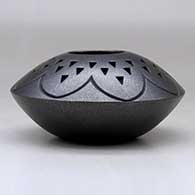 A black micaceous jar decorated with a lightly carved geometric design and a corrugated geometric design above the shoulder, click or tap to see a larger version