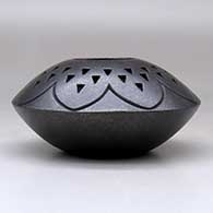A black micaceous jar decorated with a lightly carved geometric design and a corrugated geometric design above the shoulder, click or tap to see a larger version