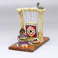 A Navajo Lifestyle piece with a woman sitting near her weaving loom with a welcome basket, dog, cat and hanging carpet
 by Elizabeth Manygoats of Dineh