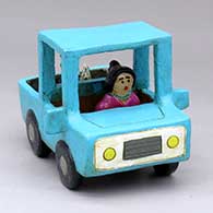 A woman driving a polychrome pickup with a dog in the back
 by Elizabeth Manygoats of Dineh