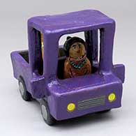 A woman driving a polychrome pickup with a dog in the back
 by Elizabeth Manygoats of Dineh