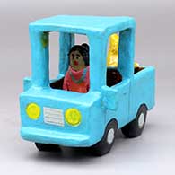 A woman in a polychrome pickup with a dog in the back
 by Elizabeth Manygoats of Dineh