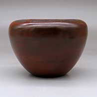 A brown jar with a flat top decorated with a sgraffito geometric design above the shoulder and fire clouds, click or tap to see a larger version