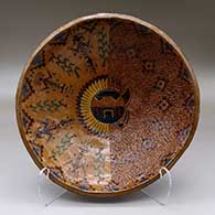 A shallow polychrome bowl decorated with a sgraffito and painted yeibichai, sun shield, feather and geometric design
 by Nancy Yazzie of Dineh