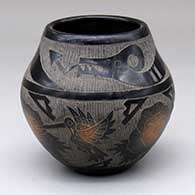 A black jar with sienna spots and a sgraffito avanyu, hummingbird, flower and geometric design
 by Melvin Moquino of Santa Clara