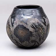 A black jar with dark sienna spots and a four-panel sgraffito butterfly, flower and geometric design
 by Melvin Moquino of Santa Clara