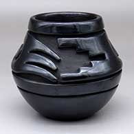 A black jar carved with a stylized avanyu and geometric design above the shoulder
 by Teresita Naranjo of Santa Clara