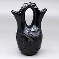 A black wedding vase with a twisted bridge and carved with an avanyu and geometric design around the body
 by Joe Naranjo of Santa Clara