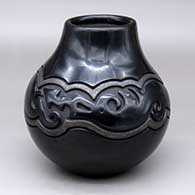 A black jar carved with an avanyu design bordered with a band of carved micaceous black geometric design
 by Linda Tafoya of Santa Clara