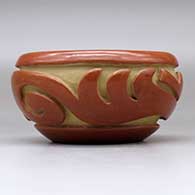 A red bowl decorated with a stylized avanyu design carved around the body, click or tap to see a larger version