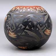 A black bowl with a sienna rim and spots, decorated with a sgraffito avanyu and geometric design with an inlaid stone, click or tap to see a larger version