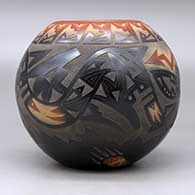 A black bowl with a sienna rim and spots, decorated with a sgraffito avanyu and geometric design with an inlaid stone, click or tap to see a larger version