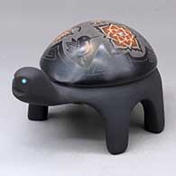 A black turtle figure decorated with sienna spots and a sgraffito hummingbird, flower, butterfly and geometric design, plus inlaid stones
 by Melony Gutierrez of Santa Clara