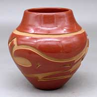 A polished red jar decorated with a carved avanyu and geometric design around the shoulder
 by Sherry Tafoya of Santa Clara