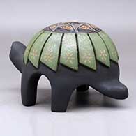 A polychrome turtle figure carved with a feather design and decorated on top with a sgraffito hummingbird, flower and geometric design plus inlaid stones, click or tap to see a larger version